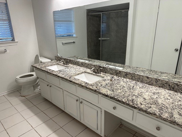 bathroom with tile patterned flooring, vanity, an enclosed shower, and toilet