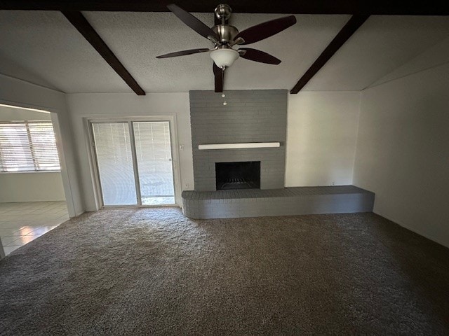 unfurnished living room featuring carpet, ceiling fan, a fireplace, a textured ceiling, and beam ceiling