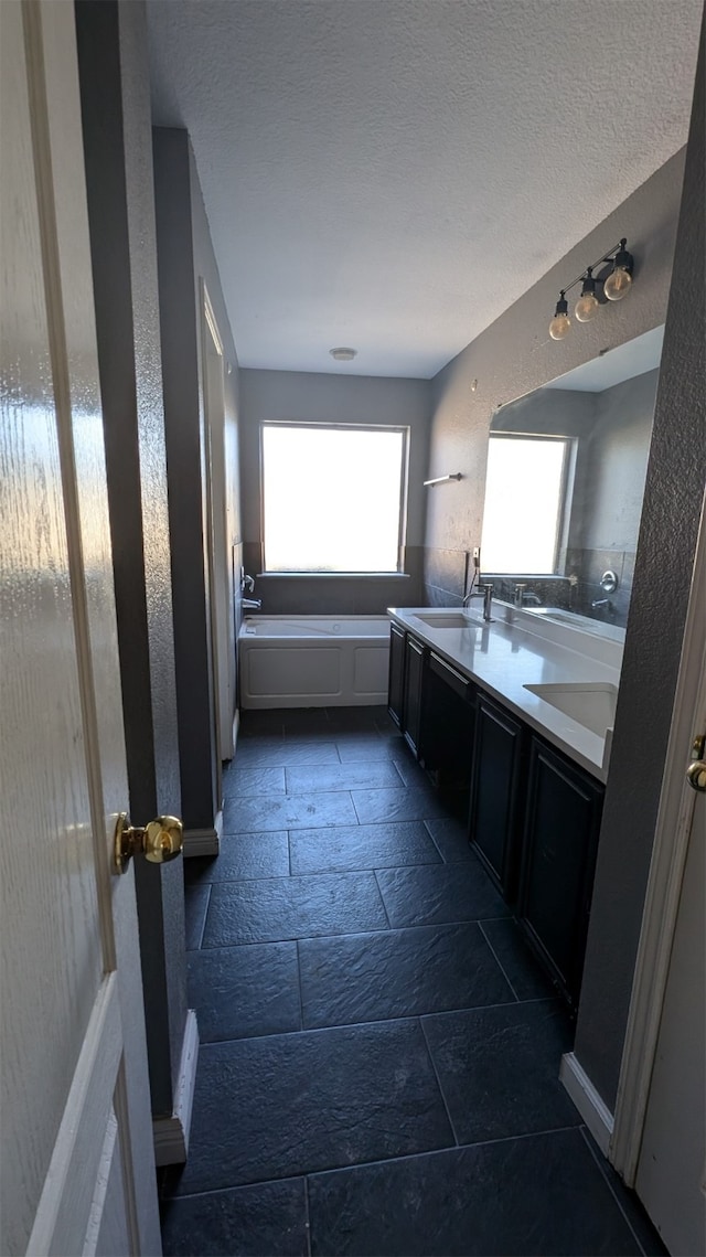 bathroom featuring a textured ceiling, tile patterned flooring, a tub to relax in, and vanity