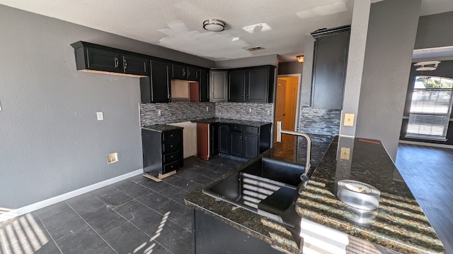 kitchen with tasteful backsplash, dark stone countertops, sink, and dark hardwood / wood-style floors