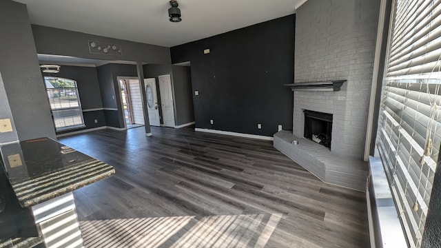 unfurnished living room featuring dark hardwood / wood-style floors and a brick fireplace