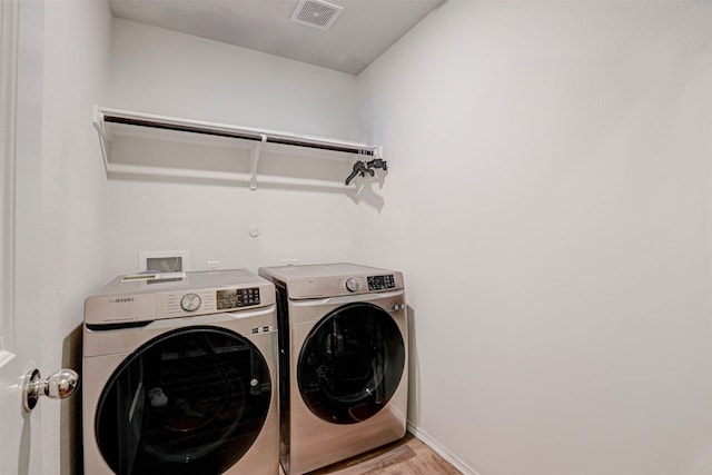 laundry room featuring separate washer and dryer and light hardwood / wood-style flooring