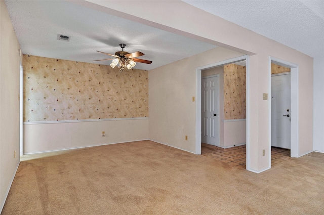 carpeted empty room with ceiling fan and a textured ceiling