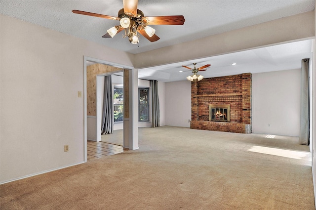 unfurnished living room featuring ceiling fan, light colored carpet, a textured ceiling, and a brick fireplace