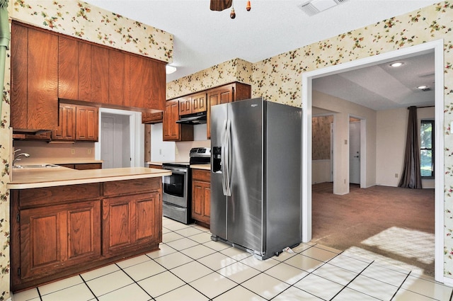 kitchen with sink, stainless steel appliances, kitchen peninsula, a textured ceiling, and light carpet