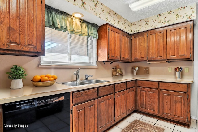 kitchen featuring a textured ceiling, sink, light tile patterned floors, and black dishwasher