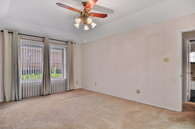 carpeted empty room with a textured ceiling, a raised ceiling, and ceiling fan