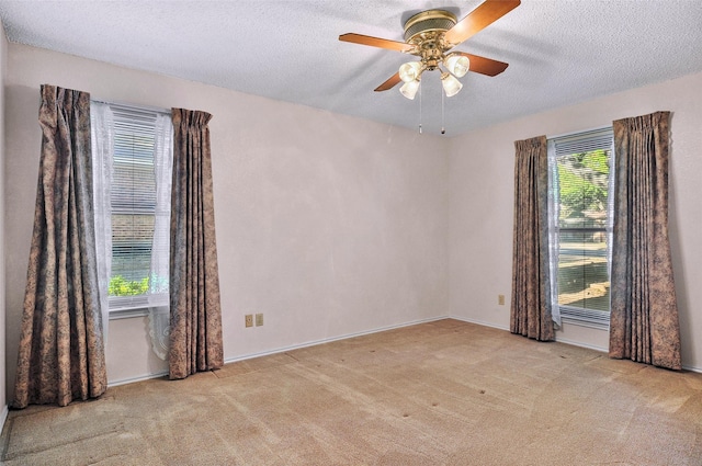 carpeted empty room with a textured ceiling, a wealth of natural light, and ceiling fan