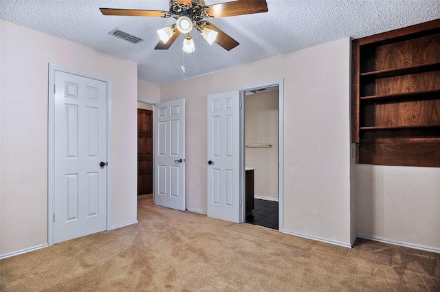 unfurnished bedroom featuring ceiling fan, light colored carpet, and a textured ceiling