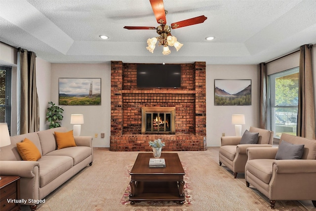 living room with light carpet, a brick fireplace, a raised ceiling, and ceiling fan