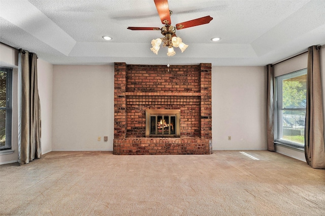 unfurnished living room featuring ceiling fan, a raised ceiling, and light colored carpet