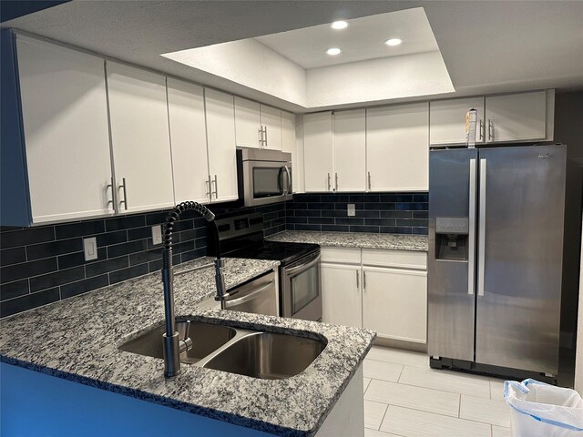 kitchen featuring stone countertops, white cabinetry, appliances with stainless steel finishes, and tasteful backsplash