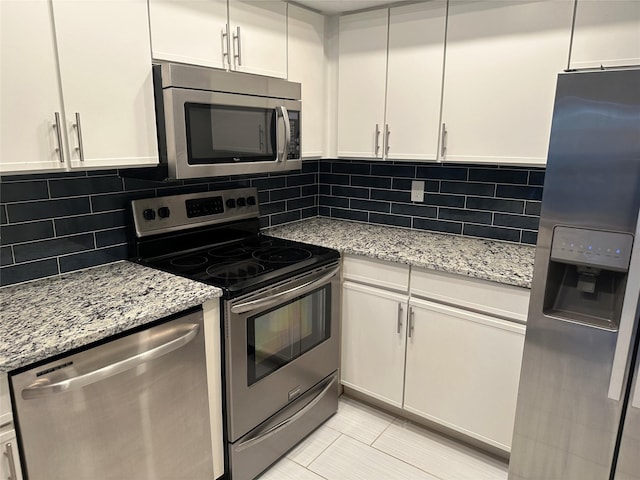 kitchen featuring white cabinets, decorative backsplash, light stone counters, and stainless steel appliances