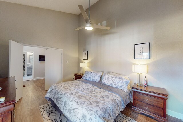 bedroom with a high ceiling, hardwood / wood-style flooring, and ceiling fan