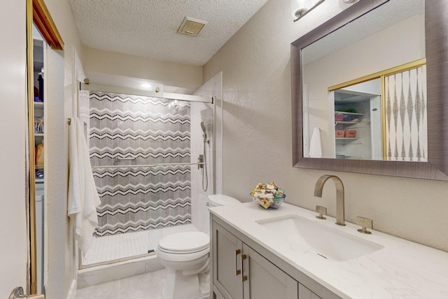 bathroom with tile patterned flooring, a shower, a textured ceiling, toilet, and vanity