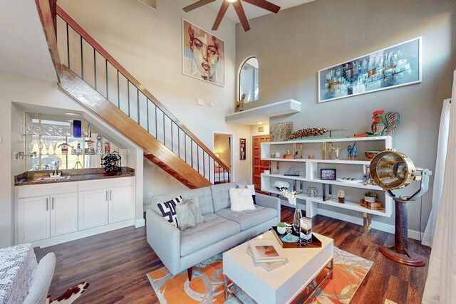 living room with ceiling fan, sink, a towering ceiling, and dark hardwood / wood-style floors