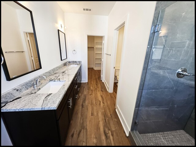 bathroom featuring vanity, wood-type flooring, a shower with shower door, and toilet