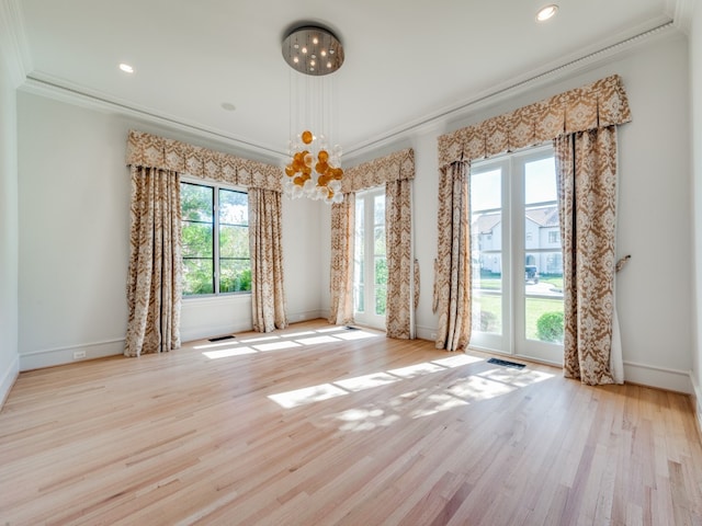 empty room featuring light hardwood / wood-style floors, crown molding, and a chandelier