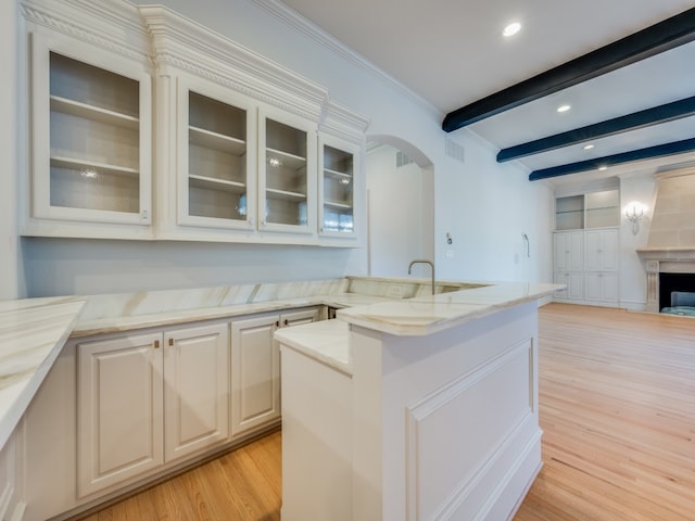 kitchen featuring beamed ceiling, light hardwood / wood-style floors, light stone counters, and ornamental molding