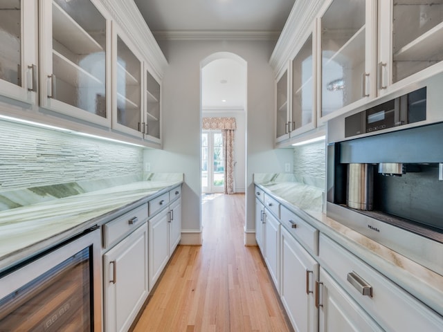 kitchen featuring backsplash, ornamental molding, beverage cooler, light hardwood / wood-style flooring, and white cabinets