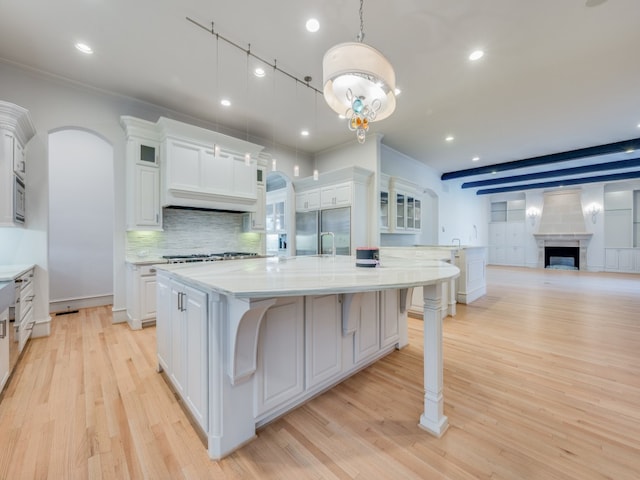 kitchen with a large island, stainless steel appliances, a kitchen breakfast bar, pendant lighting, and white cabinets