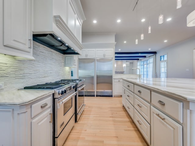 kitchen with premium appliances, premium range hood, white cabinetry, and a spacious island