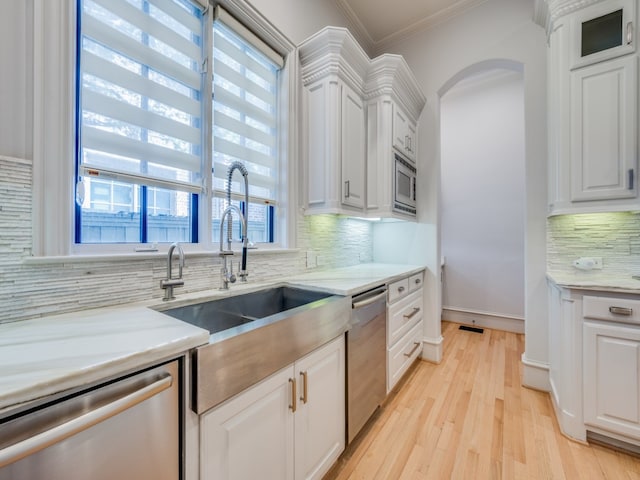 kitchen featuring white cabinets, appliances with stainless steel finishes, backsplash, and light hardwood / wood-style floors