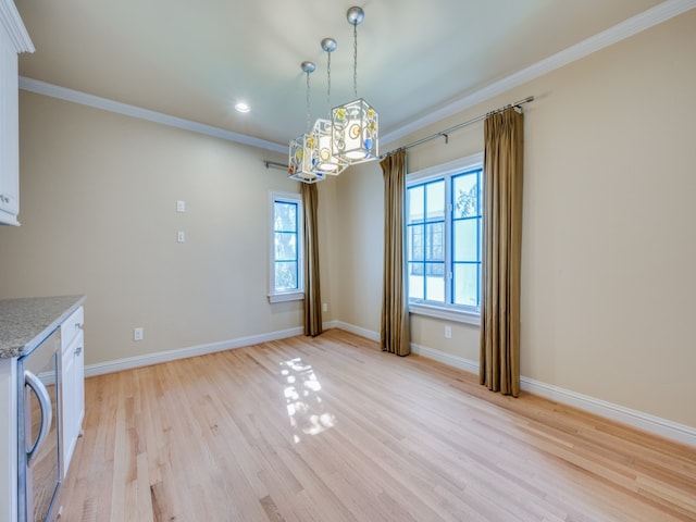 unfurnished dining area with beverage cooler, ornamental molding, a wealth of natural light, and light hardwood / wood-style flooring