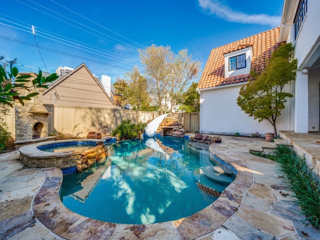 view of swimming pool with an outdoor stone fireplace, a patio area, and an in ground hot tub