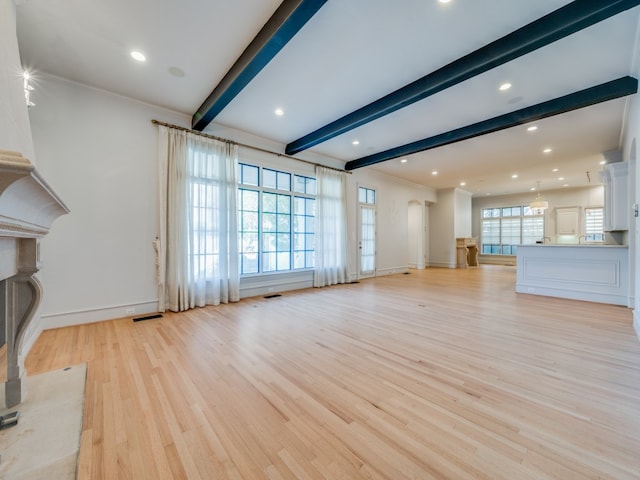 unfurnished living room with a healthy amount of sunlight, light hardwood / wood-style floors, and beam ceiling