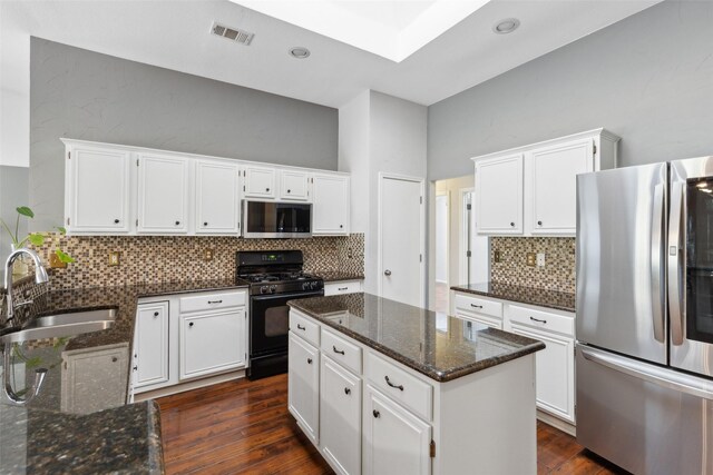 kitchen with appliances with stainless steel finishes, dark hardwood / wood-style floors, white cabinetry, and sink