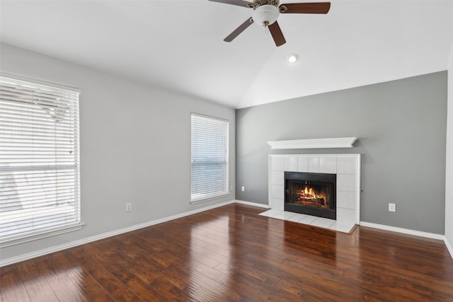 unfurnished living room featuring hardwood / wood-style floors, a healthy amount of sunlight, a tile fireplace, and vaulted ceiling