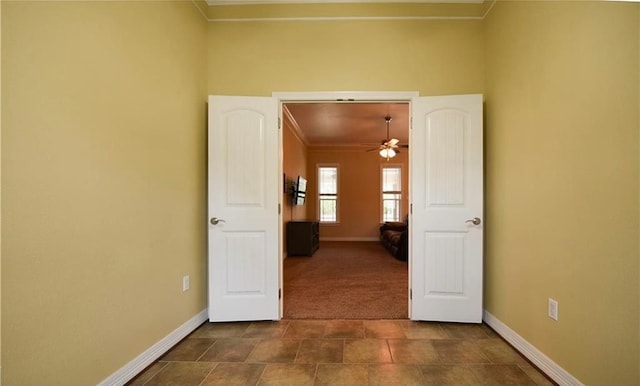 interior space featuring ceiling fan, dark carpet, and ornamental molding