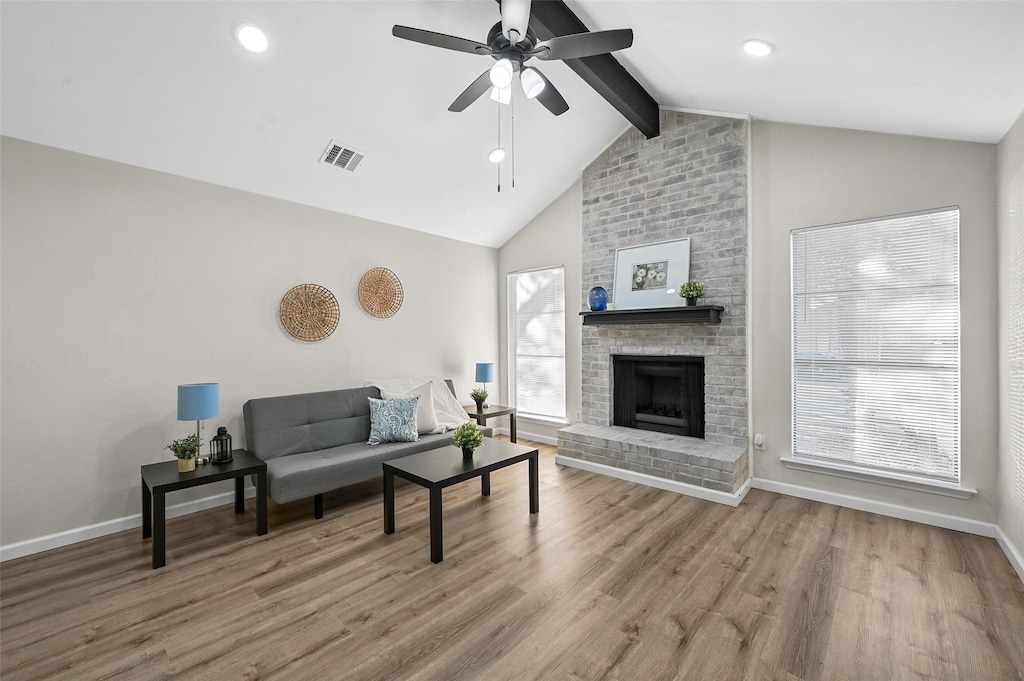 living room featuring lofted ceiling with beams, a fireplace, ceiling fan, and wood-type flooring