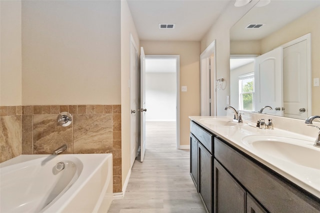 bathroom with hardwood / wood-style flooring, vanity, and a bathtub