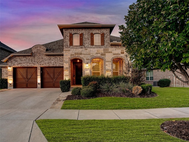 view of front of home featuring central AC, a garage, and a lawn