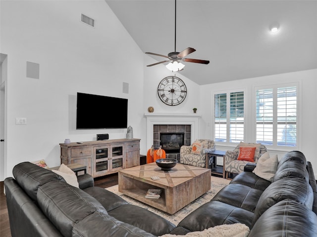 living room with a tiled fireplace, ceiling fan, high vaulted ceiling, and dark hardwood / wood-style floors