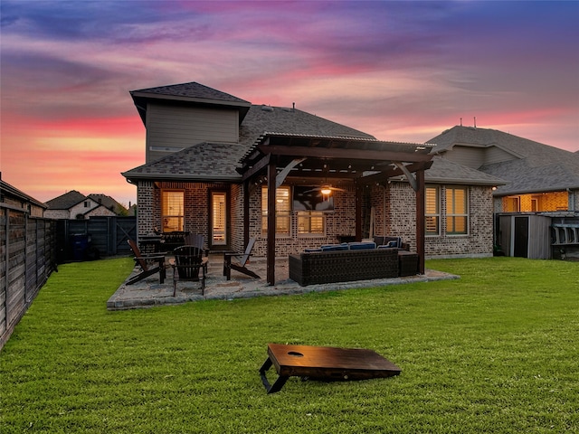 back house at dusk featuring an outdoor living space, a patio area, and a yard