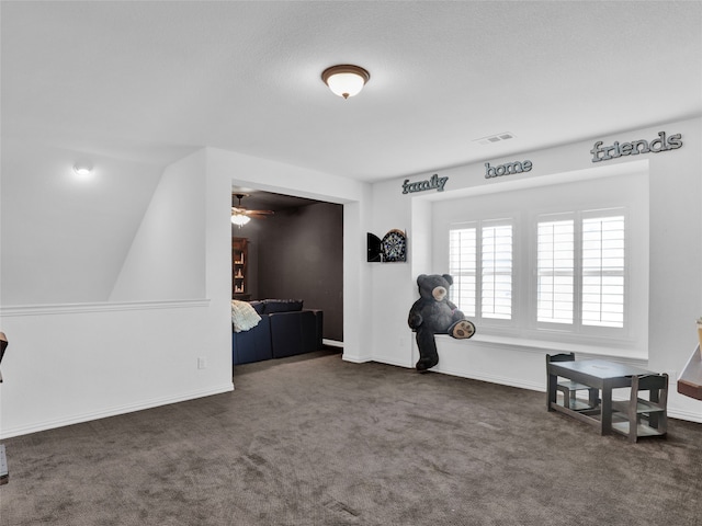 interior space featuring a textured ceiling, ceiling fan, dark carpet, and lofted ceiling