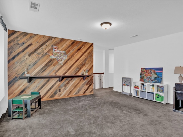 recreation room featuring dark carpet and wood walls