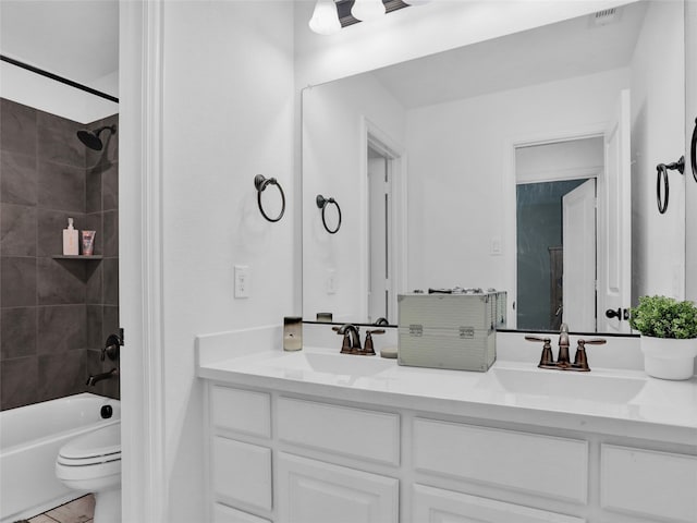 full bathroom featuring vanity, tiled shower / bath combo, and toilet