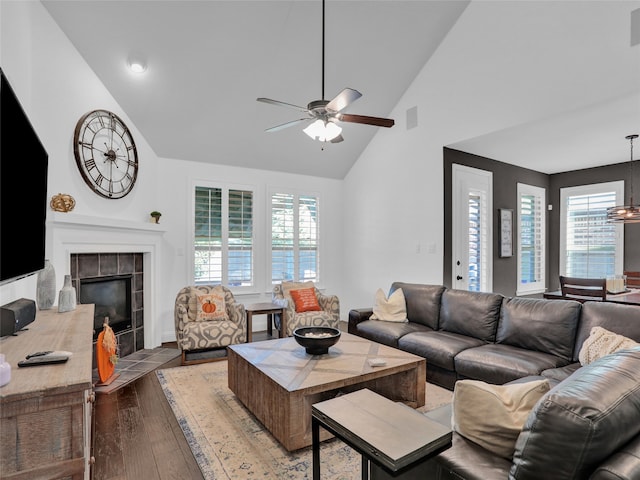 living room featuring high vaulted ceiling, light wood-type flooring, a fireplace, and a wealth of natural light