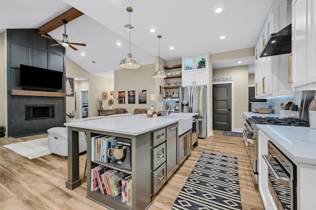 kitchen with stainless steel appliances, white cabinets, an island with sink, and light wood-type flooring