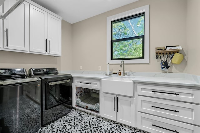 clothes washing area featuring washer and clothes dryer, cabinets, and sink