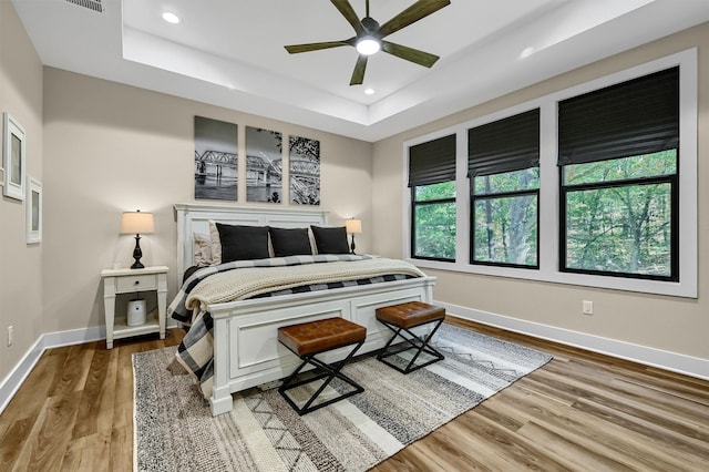 bedroom with a tray ceiling, ceiling fan, and hardwood / wood-style floors