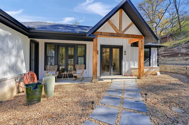 rear view of property with board and batten siding, french doors, and a shingled roof