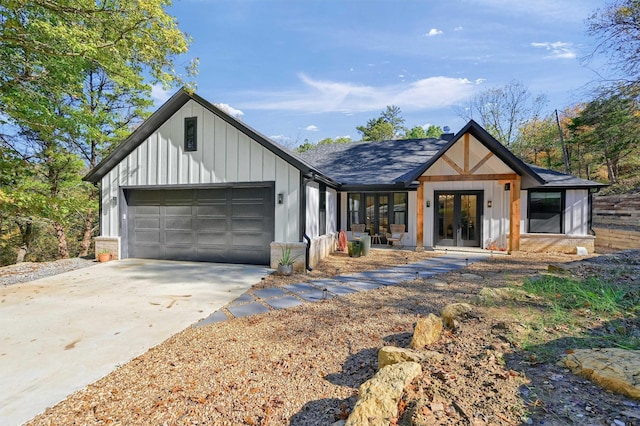 modern inspired farmhouse with an attached garage, board and batten siding, concrete driveway, and french doors