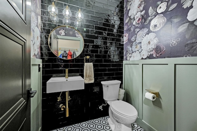 bathroom with tile patterned flooring, toilet, tile walls, and sink