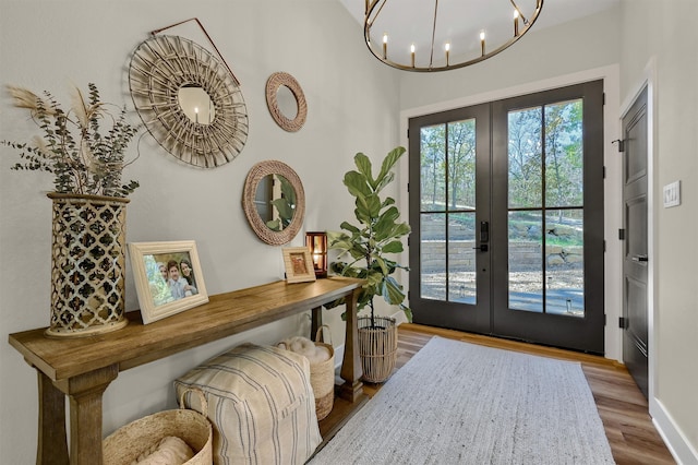 entryway with hardwood / wood-style floors, a notable chandelier, and french doors