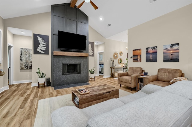 living room with light wood-type flooring, a large fireplace, ceiling fan, beam ceiling, and high vaulted ceiling